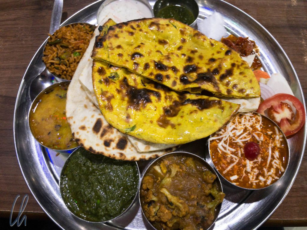 Ein vegetarisches Thali mit Dal, einem Blumenkohl-Curry, Palak Paneer, Reis, Raita und Naan