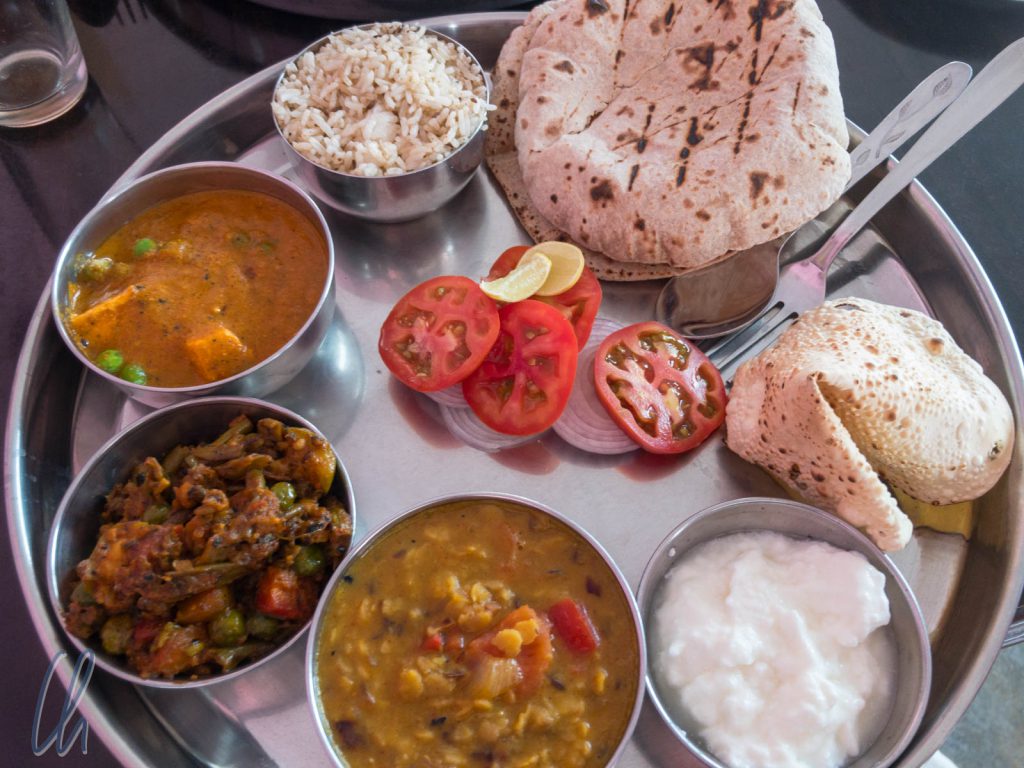Ein vegetarisches Thali mit Mattar Paneer, einem Okra-Gericht, Dal, Reis, Chapati, Papadam und Joghurt