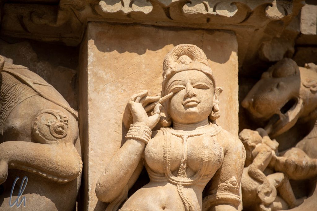 Eine Surasundari schminkt sich am Parshvanath Tempel.